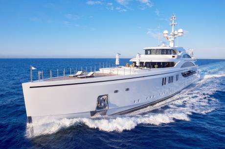 A luxurious white yacht glides through the deep blue ocean under a clear sky.
