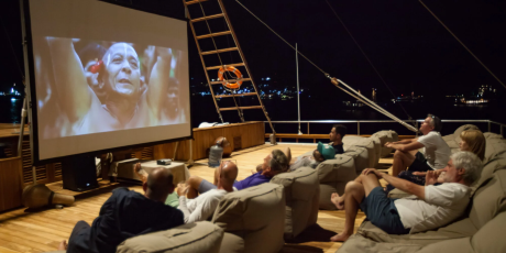 Guests enjoy an outdoor movie screening under the stars on a luxurious yacht deck.