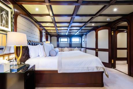 Luxurious yacht stateroom features a plush king-sized bed, elegant wood paneling, and a serene ambiance for ultimate relaxation.