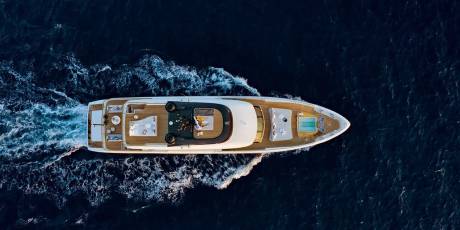 A luxurious yacht cuts through the deep blue ocean, leaving a trail of white foam in its wake.