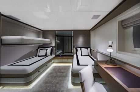Luxurious twin beds with crisp white linens and black accents are perfectly arranged in this elegant yacht cabin.