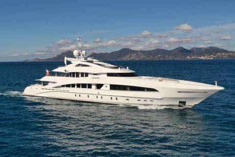 The luxurious yacht COMO I glides through the deep blue waters under a bright sky with distant mountains.