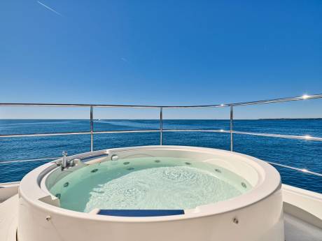 Relax in a luxurious hot tub on deck with endless ocean views under a clear blue sky.