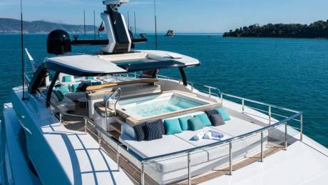 A luxurious yacht deck features a bubbling hot tub and plush seating, perfect for enjoying the serene ocean views.
