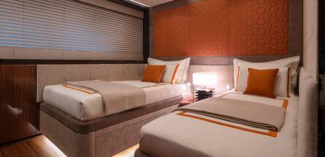 Luxurious twin beds with crisp white linens and warm orange accents create a serene retreat.