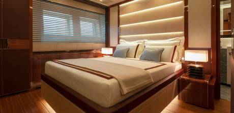 Luxurious yacht cabin features a plush bed, ambient lighting, and rich wood finishes for ultimate comfort.