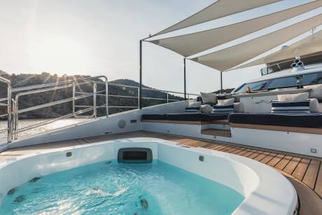 Relax in the jacuzzi on the deck of this luxurious yacht, surrounded by stunning coastal scenery.