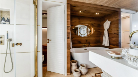 This luxurious bathroom features a freestanding tub, a sleek shower, and a vanity with a unique eye-shaped mirror.