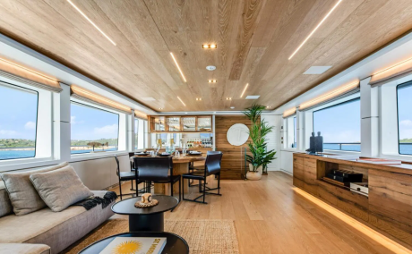 A modern yacht interior offers a serene dining and lounge area with panoramic ocean views.