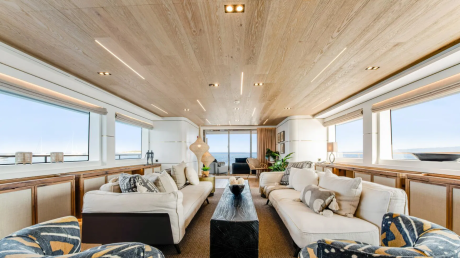 The luxurious yacht interior features comfortable seating and expansive windows offering stunning ocean views.