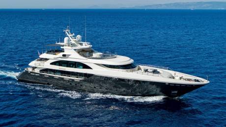 A sleek, modern yacht glides through the deep blue ocean under a clear sky.