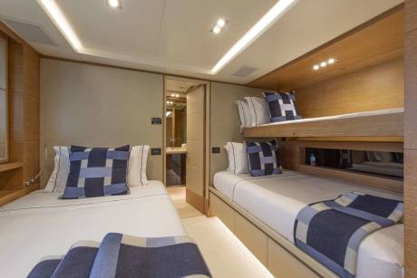 Bunk beds and a twin bed offer comfortable sleeping arrangements in this stylish yacht cabin.