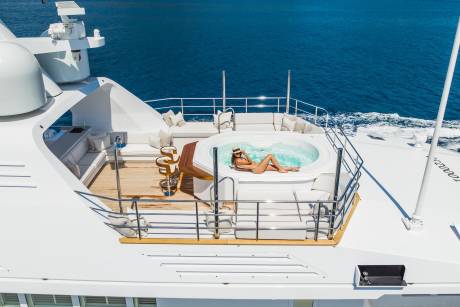 A woman relaxes in a hot tub on the deck of a luxury yacht cruising through the deep blue sea.
