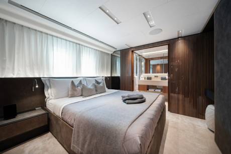 Luxurious yacht accommodations feature a plush king-sized bed and a sleek, modern ensuite bathroom.