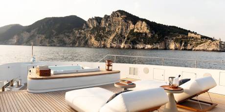 Relax in the jacuzzi or on a sun lounger aboard this luxurious yacht with a stunning coastal mountain backdrop.