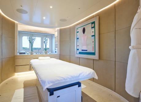 A luxurious spa room features a massage table, a serene painting, and a plush bathrobe hanging on the wall.