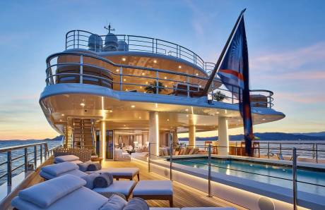 Luxurious loungers and a shimmering pool await on the deck of this opulent yacht at sunset.