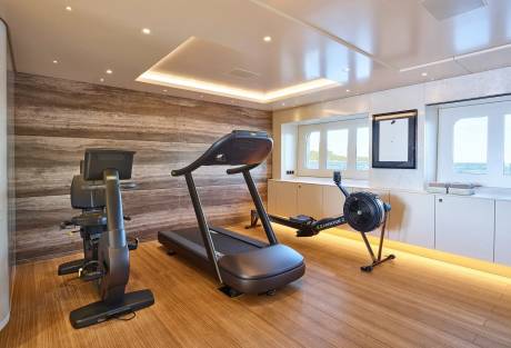 This modern yacht gym offers a treadmill, stationary bike, and rowing machine with ocean views.