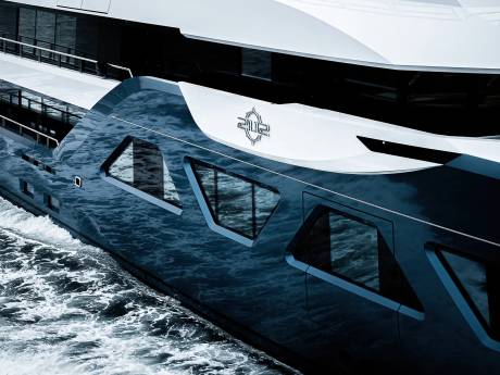 A large, sleek white yacht with a distinctive logo on its side, cutting through the choppy blue waters in the background.