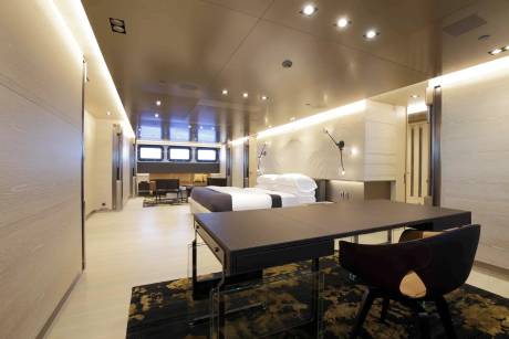 Luxurious yacht interiors feature a spacious bedroom with a modern desk and a cozy seating area.