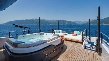 Relax in the bubbling hot tub on the deck of this luxurious yacht, with stunning mountain views in the distance.