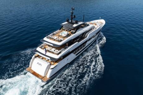 A luxurious white yacht glides through deep blue waters, leaving a foamy wake in its path.