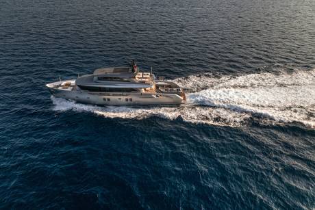 A sleek, modern yacht glides through the deep blue ocean, leaving a foamy white wake in its path.