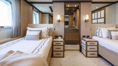 Luxurious twin beds flank a marble-accented bathroom, offering a serene retreat on this elegant yacht.