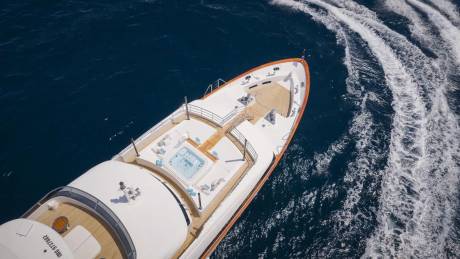 A luxurious yacht glides through deep blue waters, leaving a foamy white wake in its powerful path.