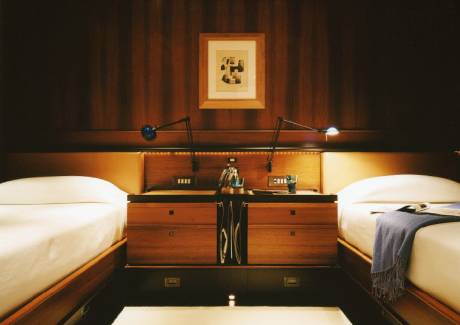 Luxurious twin beds are perfectly appointed with reading lamps and elegant wooden nightstands in this sophisticated cabin.