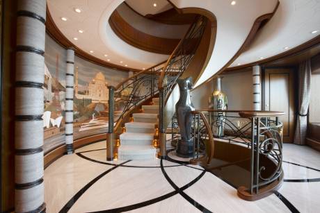 A grand staircase with intricate metalwork and a stunning mural of world landmarks sets a luxurious tone.