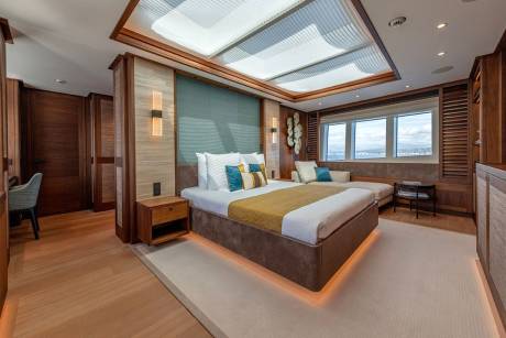 Luxurious yacht cabin features a plush king-sized bed, elegant wood accents, and panoramic ocean views.
