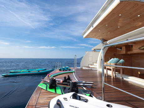 Paddleboards and water toys await adventure on the deck of this luxurious yacht at sea.
