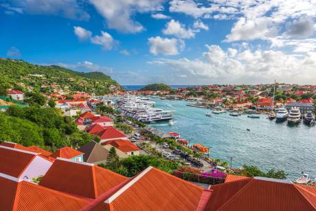 Luxury yachts fill the harbor of this vibrant coastal town nestled against lush green hills.