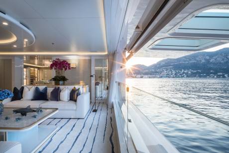 Sunlight glints off the water as the luxurious yacht glides past a picturesque coastal town.