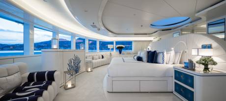 Luxurious yacht bedroom offers stunning ocean views and elegant white and blue decor.