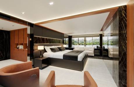 Luxurious modern bedroom with a king-size bed, marble accents, and panoramic windows overlooking a lush green landscape.