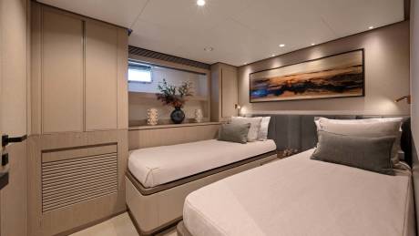 This elegant stateroom features two twin beds, a soothing color palette, and a captivating abstract artwork above the headboard.