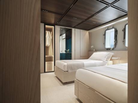 Twin beds with crisp white linens and light wood accents create a serene retreat aboard this luxurious yacht.