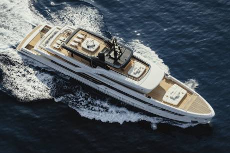 A sleek white yacht glides through the deep blue ocean, leaving a trail of white foam in its wake.