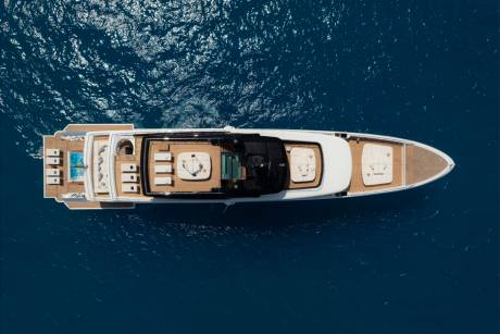 A luxurious yacht glides through the deep blue ocean, its deck adorned with plush seating and a sparkling pool.