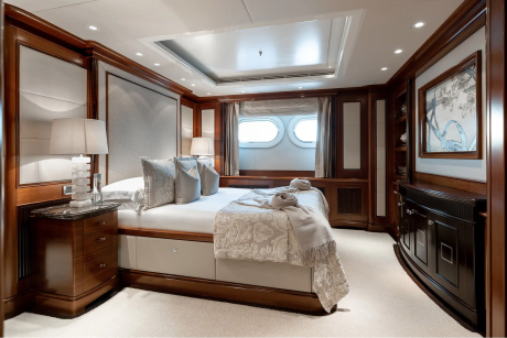 Luxurious yacht stateroom features rich wood paneling, plush bedding, and elegant decorative accents.
