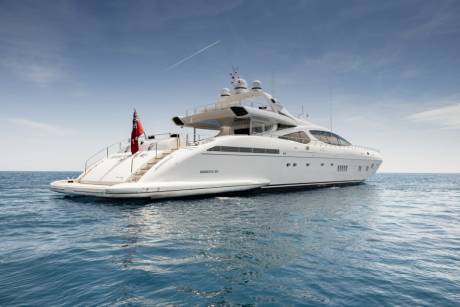 A luxurious white yacht glides across the serene blue waters under a clear sky.