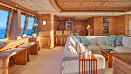 Luxurious yacht interiors feature warm wood paneling, plush seating, and large windows offering stunning ocean views.