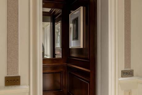A dimly lit hallway with wooden paneling and a framed artwork on the wall, leading to a partially visible doorway.
