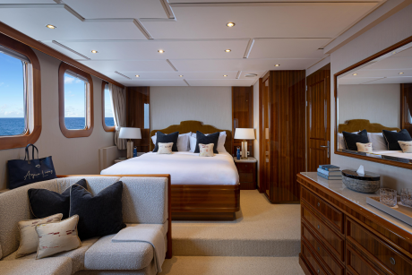 A luxurious and spacious bedroom with large windows overlooking the ocean, featuring a plush bed, wooden furniture, and cozy seating area.