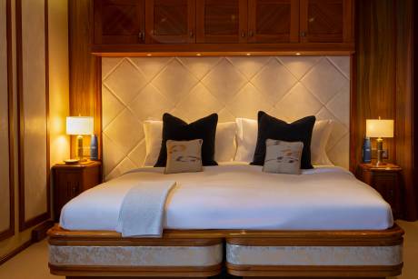 A cozy and inviting bedroom with a plush bed, wooden furniture, and decorative lighting, creating a warm and comfortable atmosphere.