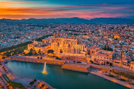 A breathtaking cityscape with a magnificent cathedral at the center, surrounded by a vibrant urban landscape, all set against a stunning sunset sky with vibrant hues of orange, pink, and blue.