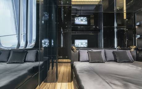 A modern and sleek interior design with a cozy seating area featuring plush gray sofas and a wooden floor, surrounded by glass walls that provide a panoramic view of the exterior.