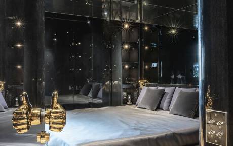 A luxurious bedroom with a large bed, plush bedding, and a mirrored wall creating a sparkling, starry atmosphere.